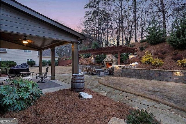 patio terrace at dusk featuring an outdoor stone fireplace