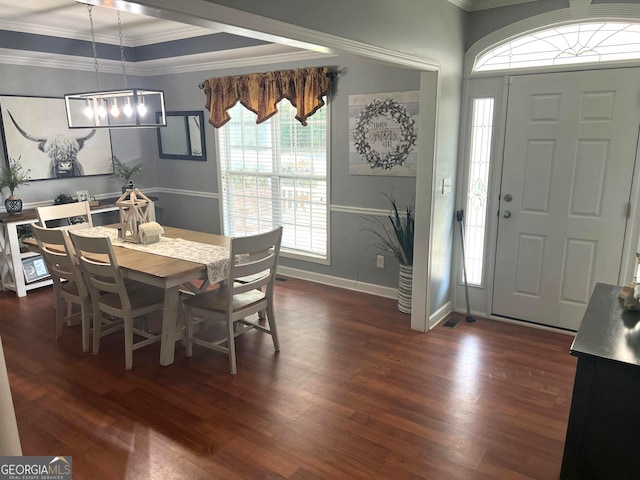 dining space featuring baseboards, a tray ceiling, ornamental molding, and dark wood-style flooring