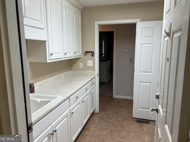 kitchen with light countertops, visible vents, white cabinets, a sink, and tile patterned flooring