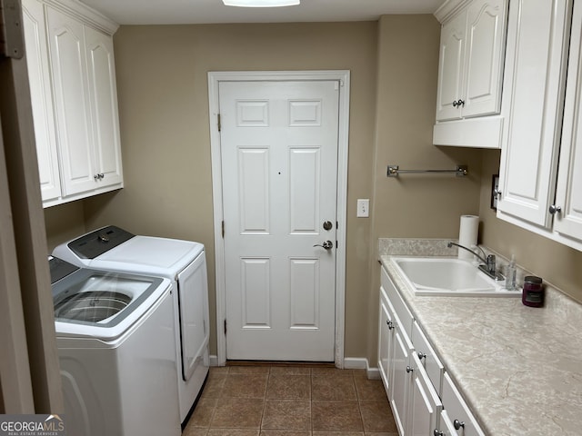 laundry area featuring washer and clothes dryer, cabinet space, a sink, dark tile patterned floors, and baseboards