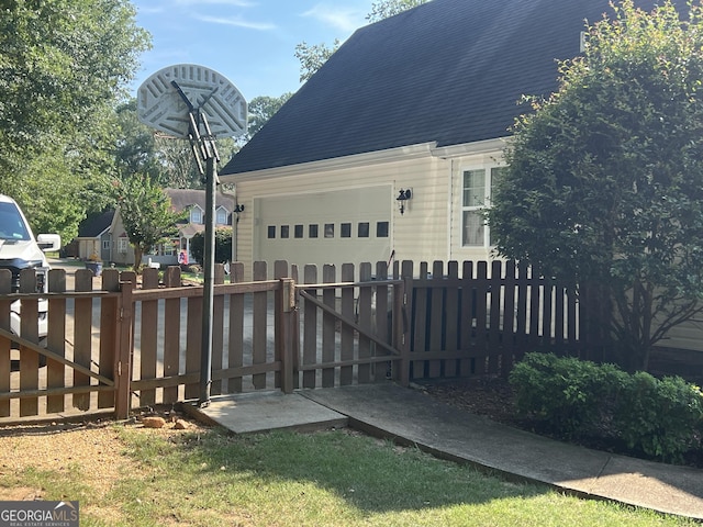 exterior space with a garage, fence, and roof with shingles