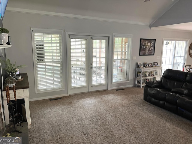 carpeted living area with baseboards, visible vents, lofted ceiling, crown molding, and french doors