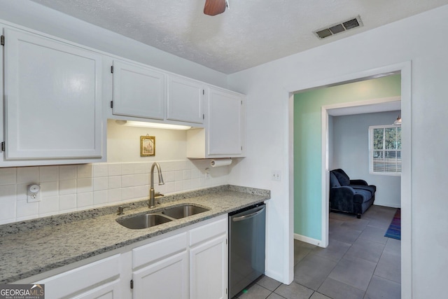 kitchen with a sink, visible vents, white cabinetry, stainless steel dishwasher, and backsplash