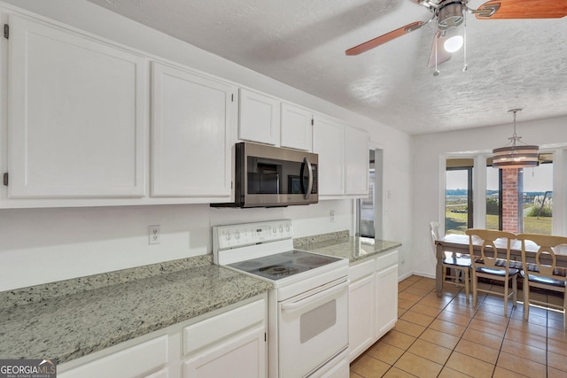 kitchen featuring a textured ceiling, light tile patterned flooring, white cabinetry, white range with electric stovetop, and stainless steel microwave