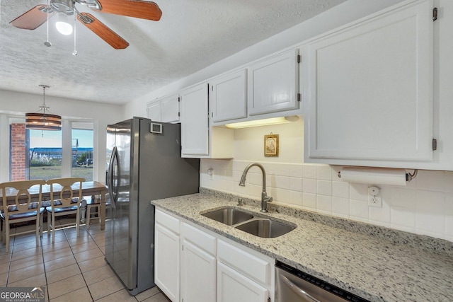 kitchen with tasteful backsplash, white cabinets, a sink, and light tile patterned floors