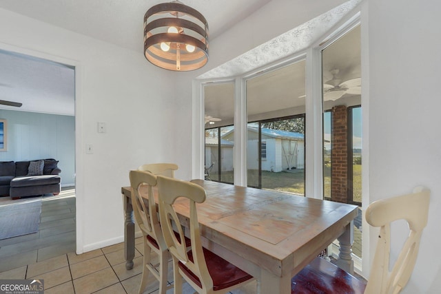 dining space with a ceiling fan, light tile patterned flooring, and baseboards