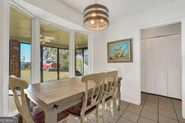 dining space with ceiling fan, baseboards, and light tile patterned floors