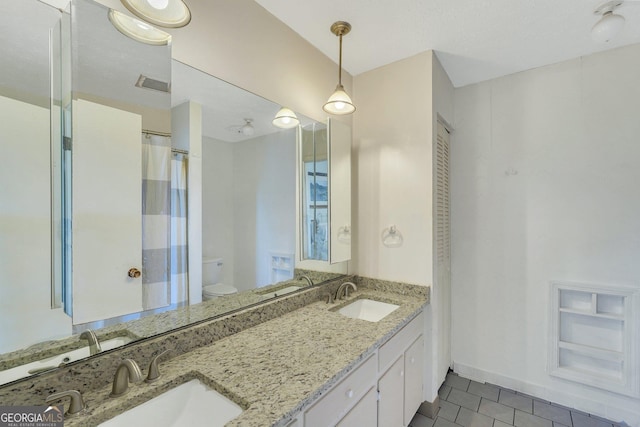 full bathroom with baseboards, a sink, toilet, and double vanity