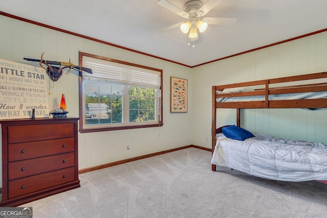 carpeted bedroom with crown molding, baseboards, and ceiling fan