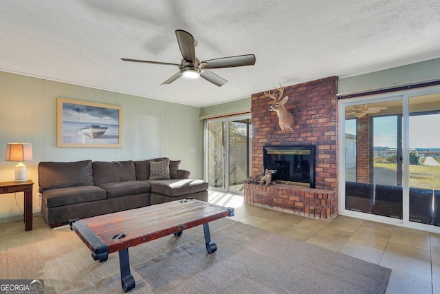 tiled living room with a textured ceiling, a fireplace, and a ceiling fan