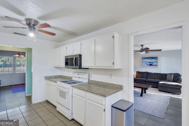 kitchen with electric stove, stainless steel microwave, visible vents, and white cabinets