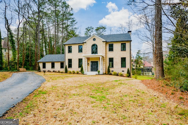 view of front facade featuring a shingled roof, a front yard, crawl space, and a chimney