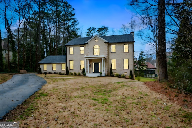 colonial inspired home with a chimney and a front lawn