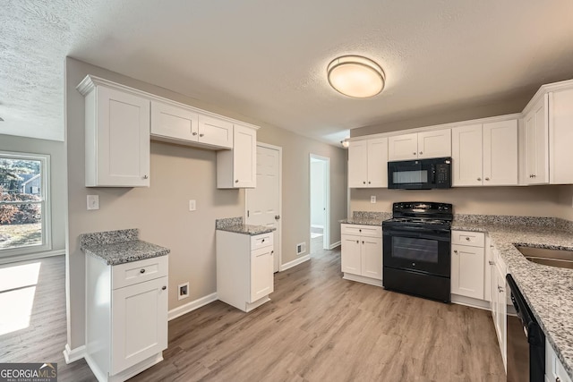 kitchen featuring a textured ceiling, black appliances, light wood-type flooring, and white cabinets