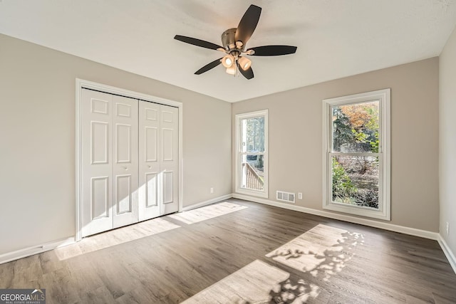 unfurnished bedroom with a closet, visible vents, baseboards, and wood finished floors