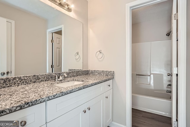 bathroom featuring a textured ceiling, shower / bathtub combination, wood finished floors, and vanity