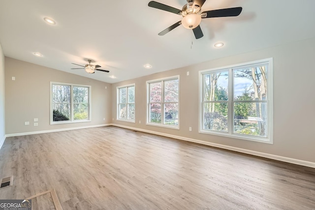 unfurnished living room with plenty of natural light, baseboards, vaulted ceiling, and wood finished floors