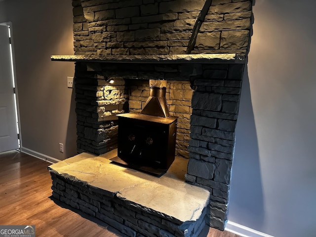 room details with a wood stove, baseboards, and wood finished floors