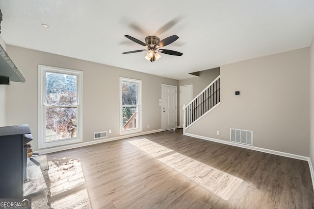 unfurnished living room with stairway, baseboards, and visible vents