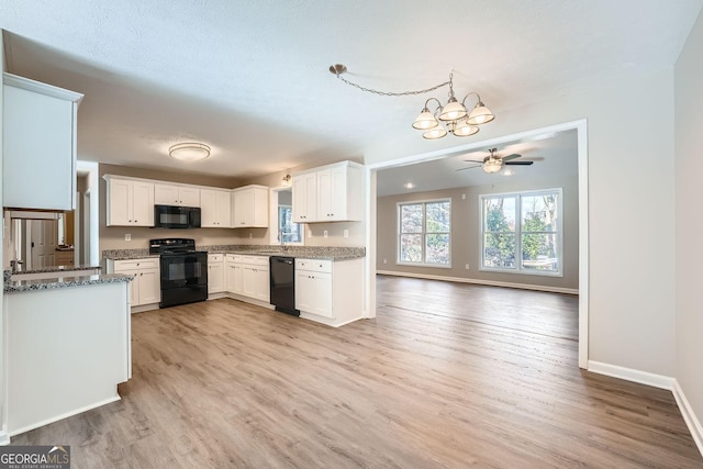 kitchen featuring baseboards, white cabinets, light stone counters, light wood-type flooring, and black appliances