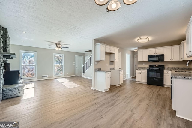 kitchen featuring light wood-style flooring, a sink, visible vents, open floor plan, and black appliances