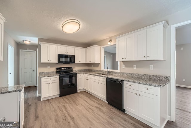 kitchen featuring black appliances, white cabinetry, light wood-style floors, and a sink