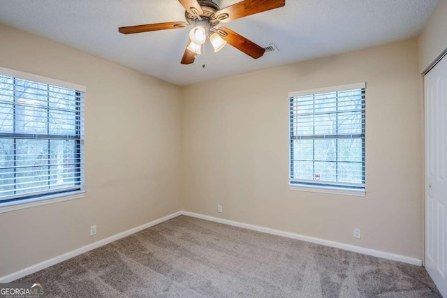 carpeted spare room featuring a textured ceiling and ceiling fan