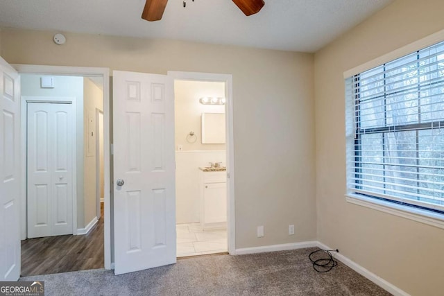 unfurnished bedroom with ensuite bathroom, carpet floors, and ceiling fan