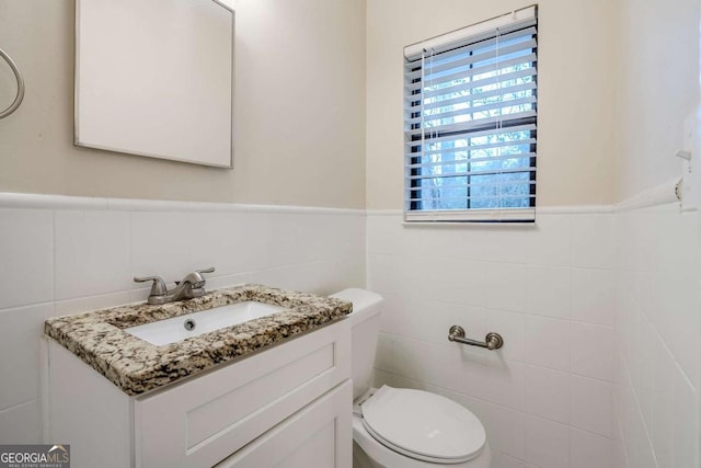 bathroom with vanity, toilet, and tile walls