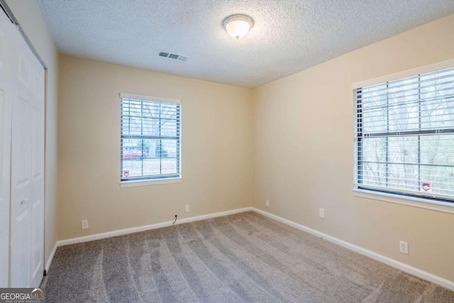 carpeted empty room featuring a textured ceiling