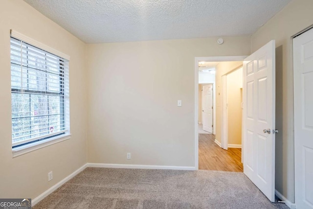 carpeted empty room featuring a textured ceiling