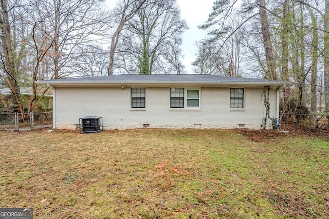 rear view of property with central AC unit and a lawn