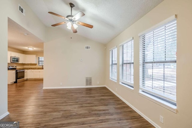 unfurnished living room featuring vaulted ceiling, dark hardwood / wood-style floors, ceiling fan, and a textured ceiling