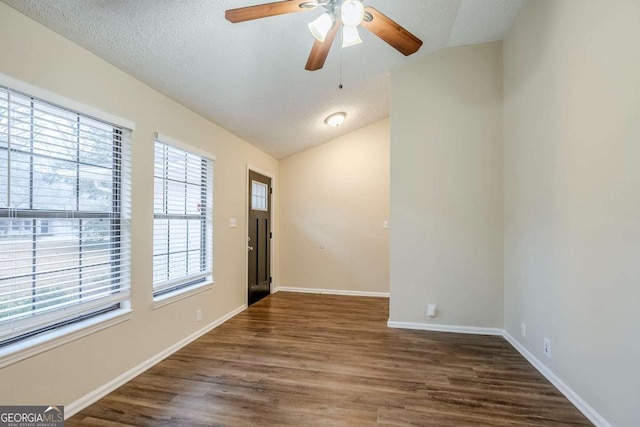 empty room with ceiling fan, lofted ceiling, dark wood-type flooring, and a textured ceiling