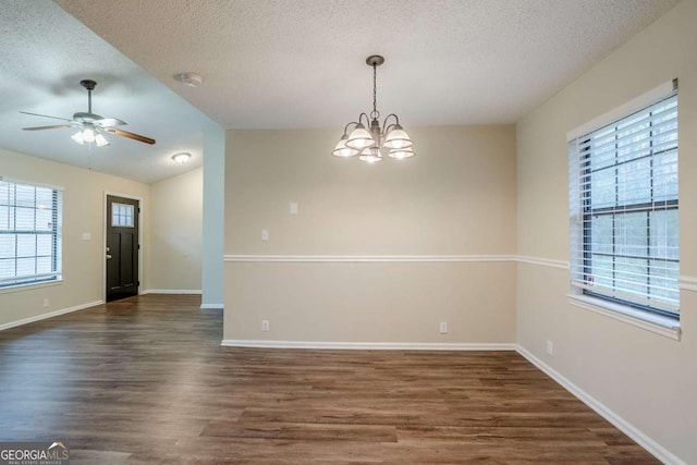 empty room featuring a textured ceiling, dark hardwood / wood-style floors, and a healthy amount of sunlight