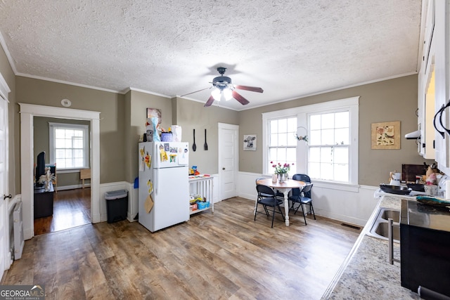 kitchen featuring ornamental molding, hardwood / wood-style flooring, white cabinets, and white fridge