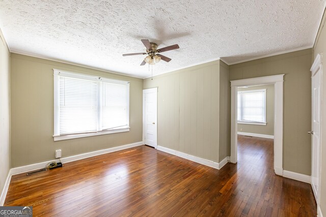 living room with ceiling fan, plenty of natural light, crown molding, and dark hardwood / wood-style flooring