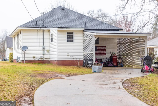 rear view of property featuring a lawn and a carport