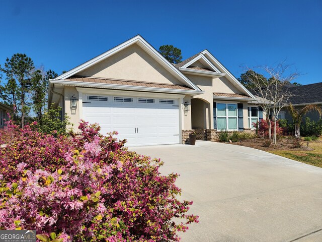 view of front facade with a garage, stucco siding, metal roof, a standing seam roof, and brick siding