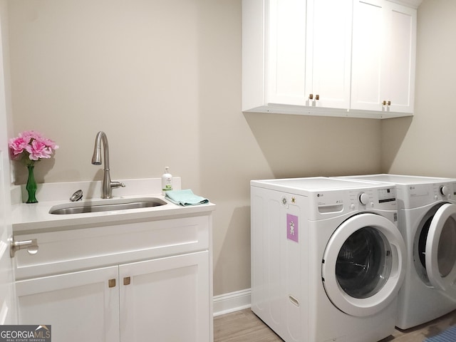 laundry room with sink, light hardwood / wood-style floors, cabinets, and independent washer and dryer