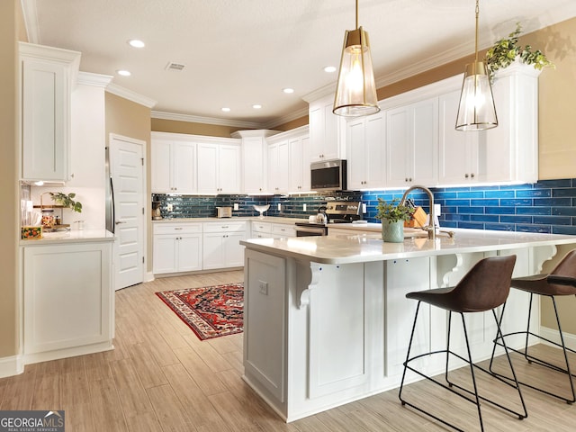 kitchen with white cabinetry, appliances with stainless steel finishes, and a kitchen breakfast bar