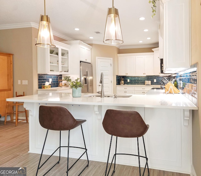 kitchen with sink, white cabinets, stainless steel fridge with ice dispenser, and hanging light fixtures