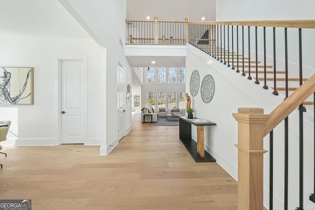 foyer entrance featuring baseboards, stairway, a high ceiling, and wood finished floors