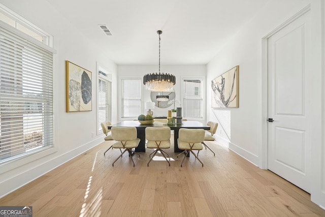 dining space with light wood-type flooring, baseboards, visible vents, and a notable chandelier