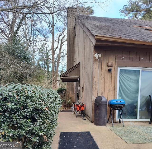 exterior space with a patio area and roof with shingles