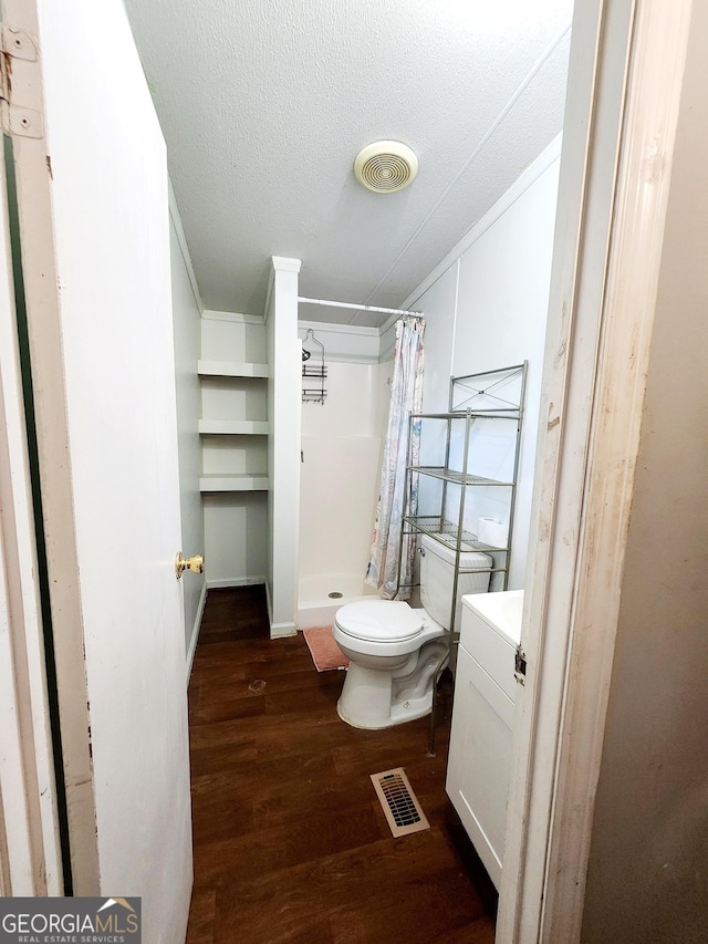 full bath featuring a textured ceiling, wood finished floors, a shower stall, and visible vents