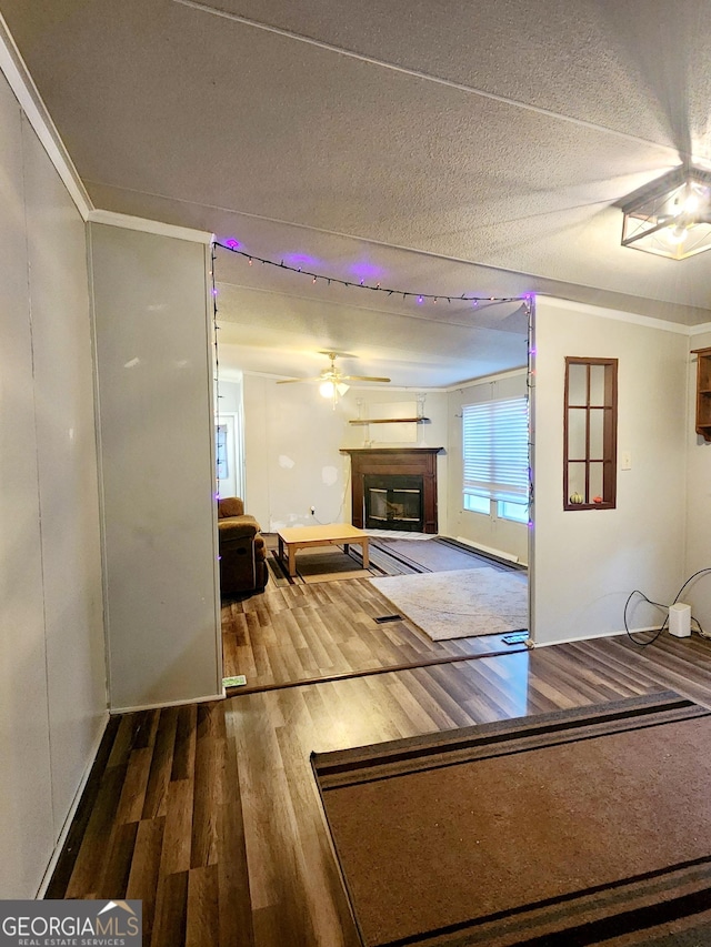 unfurnished living room with a textured ceiling, wood finished floors, and a glass covered fireplace