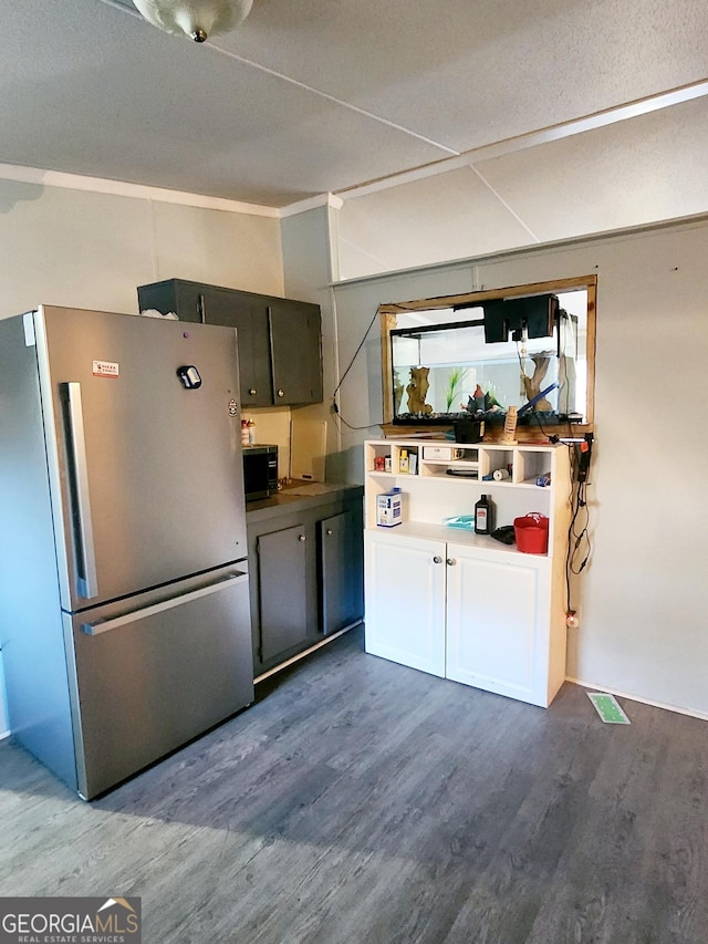 kitchen with black microwave, gray cabinets, dark wood-style flooring, and freestanding refrigerator