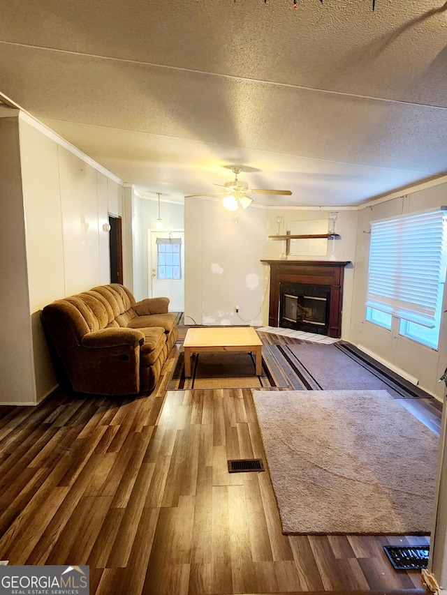 unfurnished living room with a glass covered fireplace, ceiling fan, a textured ceiling, and wood finished floors