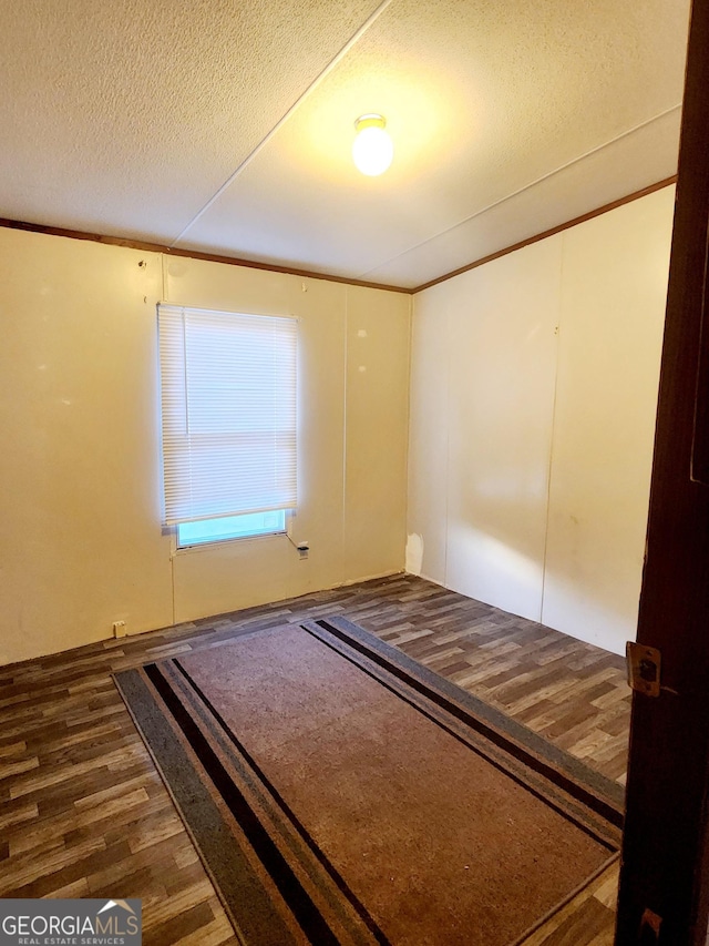 unfurnished bedroom with ornamental molding, dark wood-style flooring, and a textured ceiling